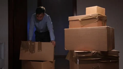 Man moving cardboard boxes during home relocation and packing Stock Footage 318982301