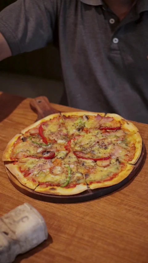 Man Moving His Hand Over A Fully Topped Sliced Pizza On A Table Stock Footage 300070347