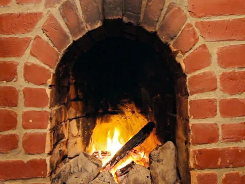 Man moving logs with a rake in a burning brick fireplace Video stock 82533568