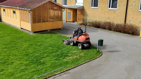 Man mowing grass beside yellow wooden house Stock Footage 313290320