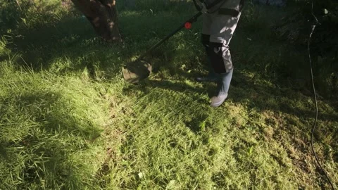Man mowing grass with electric trimmer angled top view with power cable Stock Footage 340142865