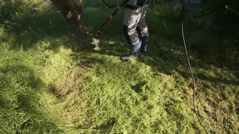 Man mowing grass with electric trimmer angled top view with power cable Stock Footage 340142885