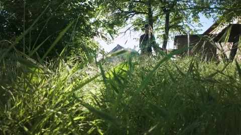 Man mowing grass with electric trimmer from ground level in slow motion backl Stock Footage 340143003