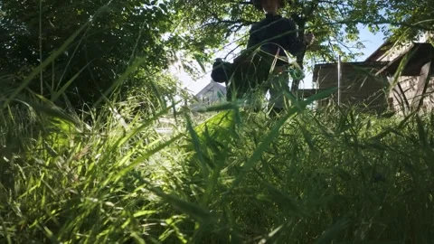 Man mowing grass with electric trimmer from ground level in slow motion backl Stock Footage 340143105