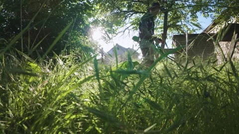 Man mowing grass with electric trimmer from ground level in slow motion backl Stock Footage 340143182