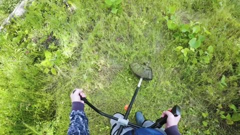 Man mowing grass with powerful electric trimmer first person slow motion Stock Footage 340143405