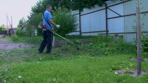 A man mowing the green grass in slow motion Stock Footage 64787989
