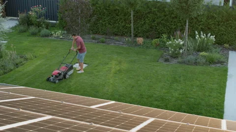 Man mowing the lawn in the backyard of the house, top view. Timelapse video Vídeo Stock 247407497