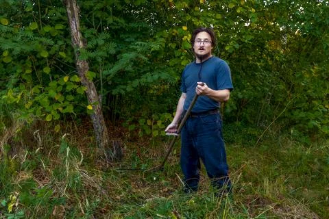 A man mows the grass with a authentic hand scythe. Stock Photos