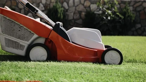 A man mows the grass in the backyard with an electric lawn mower. Slow motion Stock Footage 163033314