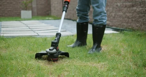 A man mows grass in backyard, with an electric lawn mower. Gardener mowing lawn. Stock-Footage 249928737