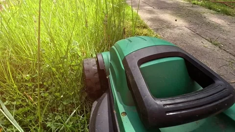 A man mows the grass in the backyard with an electric lawn mower. Stock Footage 309551067