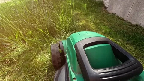 A man mows the grass in the backyard with an electric lawn mower. Stock Footage 309638386