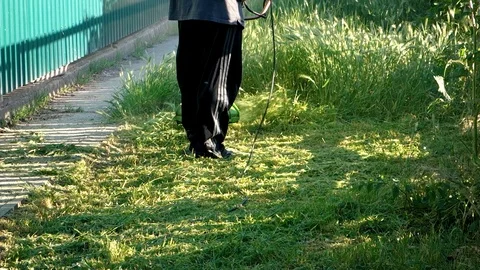 A man mows grass with a hand-held lawn mower outdoors. The gardener works in the Video stock 118755882