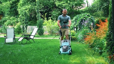 A man mows the grass with a lawn mower with a grass collector. garden design . Stock Footage 234785575