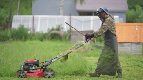 A man mows the grass with a lawnmower. 스톡 동영상 311773460