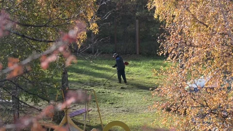 A man mows the grass with a petrol mower 動画素材 163060659