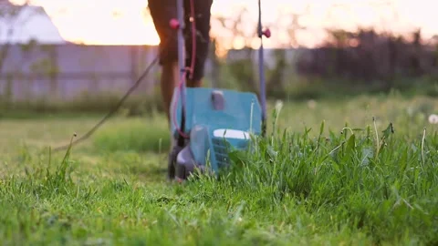 A man mows green grass in his backyard with an electric lawn mower 스톡 동영상 242171920