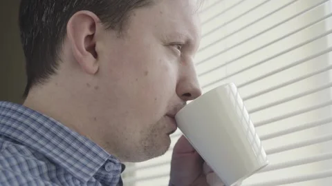 A man with a mug by the blinds Stock Footage 148978106