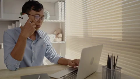 Man Multitasking, Typing on Laptop and Talking on Phone at Home Office , Home Stock Footage 263477255