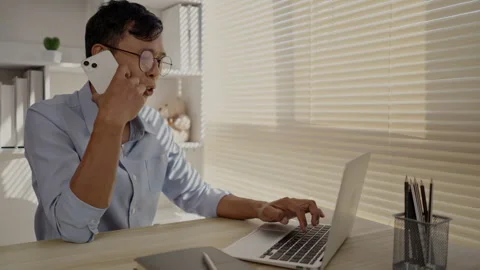 Man Multitasking, Typing on Laptop and Talking on Phone at Home Office , Home Stockbeeldmateriaal 263477502