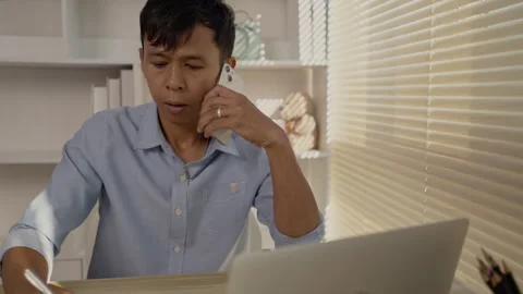 Man Multitasking, Typing on Laptop and Talking on Phone at Home Office , Home Stockbeeldmateriaal 263479544