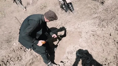 A man in Muslim clothes digs the ground with a shovel. digging a grave Stock Footage 203685537