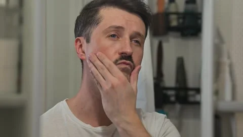 A man with a mustache admires himself and nods confidently while looking at the Vidéo 337111576
