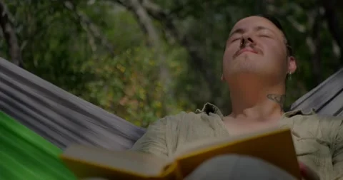Man With Mustache And Earring Reading Book In Hammock... 库存影片 331820763