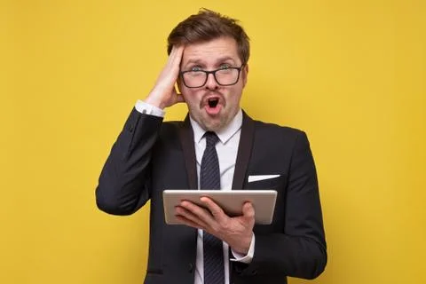 Man with mustache and glasses using tablet reading news about crisis. Stock Photos