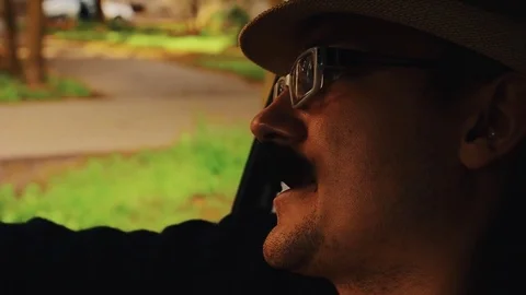 Man with mustache in hat, glasses sitting in car and sing. Parody. Hipster Video stock 75313806