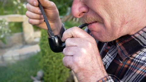 Man with a mustache smokes a pipe in the open air Stock Footage 76545808