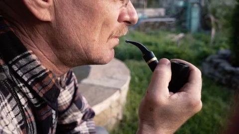 Man with a mustache smokes a pipe in the open air Stock Footage 76546481
