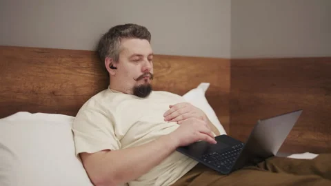 Man with a mustache working on a laptop in bed Stock Footage 340929683