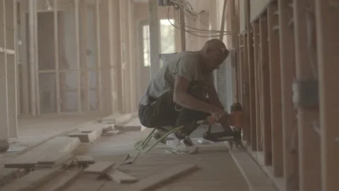 Man is nailing down hardwood flooring at a house Stock Footage 144294341