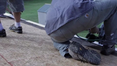 A man nails down a gutter guard on the edge of a roof. Stock Footage 94225980
