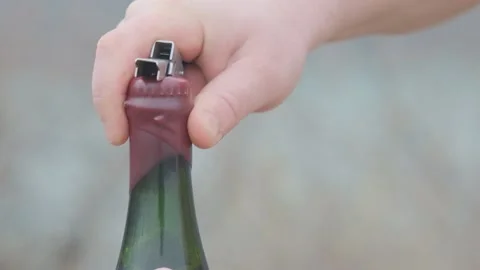 A man in nature opens a beer bottle with a bottle opener. The lid is filled with Stock Footage 185619183
