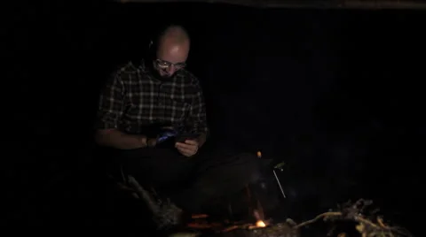 Man near campfire with tablet making video call Stock Footage 63950489