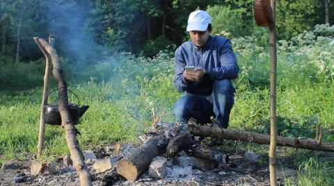Man near fire in forest call with smartphone Stock Footage 63938965