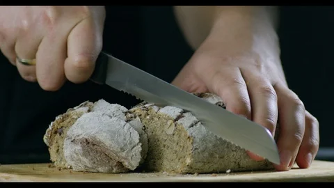 Man With A Neat Hands Cutting Bread On A Wooden Chopping Board Video stock 96197830