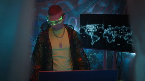 Man in Neon Visor Using Computer System for Hacking in Dark Workspace Stock Footage 327633541