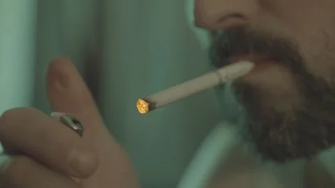 A man nervously lights a cigarette from a lighter, close-up. Video stock 299056623