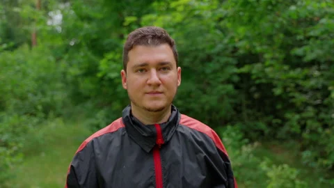 Man with neutral face looking at camera in park. 30s young person Stock Footage 158144271
