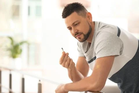 Man with nicotine patch and cigarette indoors. Space for text Stock Photos
