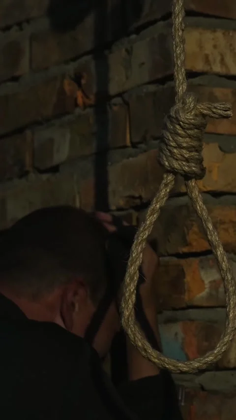 A man at night on the background of a rope with a noose for suicide. 库存影片 346339971