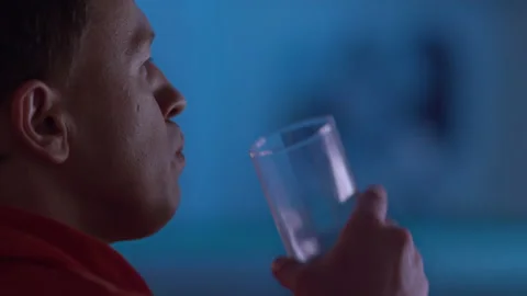 Man at night sits at the TV, drinks soda and watches a movie, multicolored Stock Footage 154558941