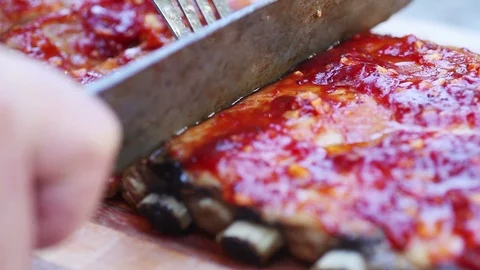 Man is not sure where to cut on barbecued ribs Stock Footage 91448141
