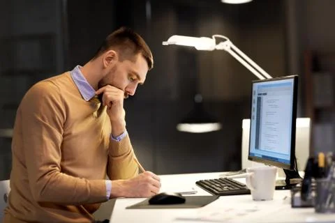 Man with notepad working on code at night office Stock Photos
