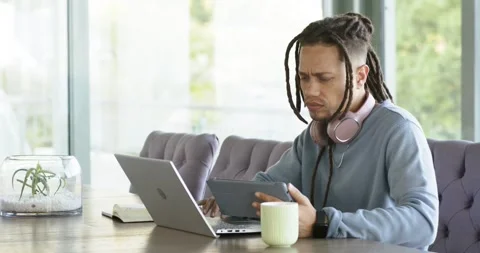 Man noticing laptop alert grabbing tablet scrolling content to compare data at Stock Footage 340010036
