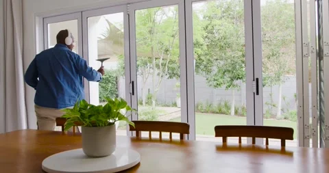 Man noticing open door, cleaning glass doors with spray bottle and squeegee at Stock Footage 344334157